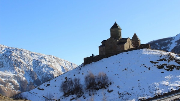 Gergeti Trinity Church on a snowy hilltop near Stepantsminda village, Georgia.