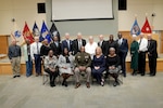 General sits while retirees participating in ceremony stand around him.
