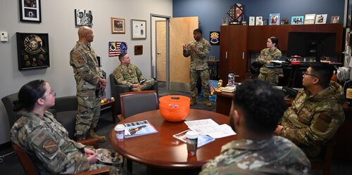 21st Security Forces members participating in the exchange event sit around a table as leadership is having a meeting.
