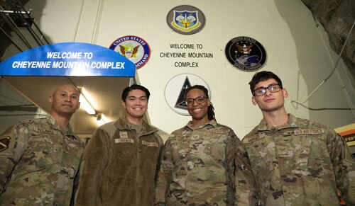 Service member pose in front of the Cheyenne Mountain Complex entrance shoulder to shoulder.