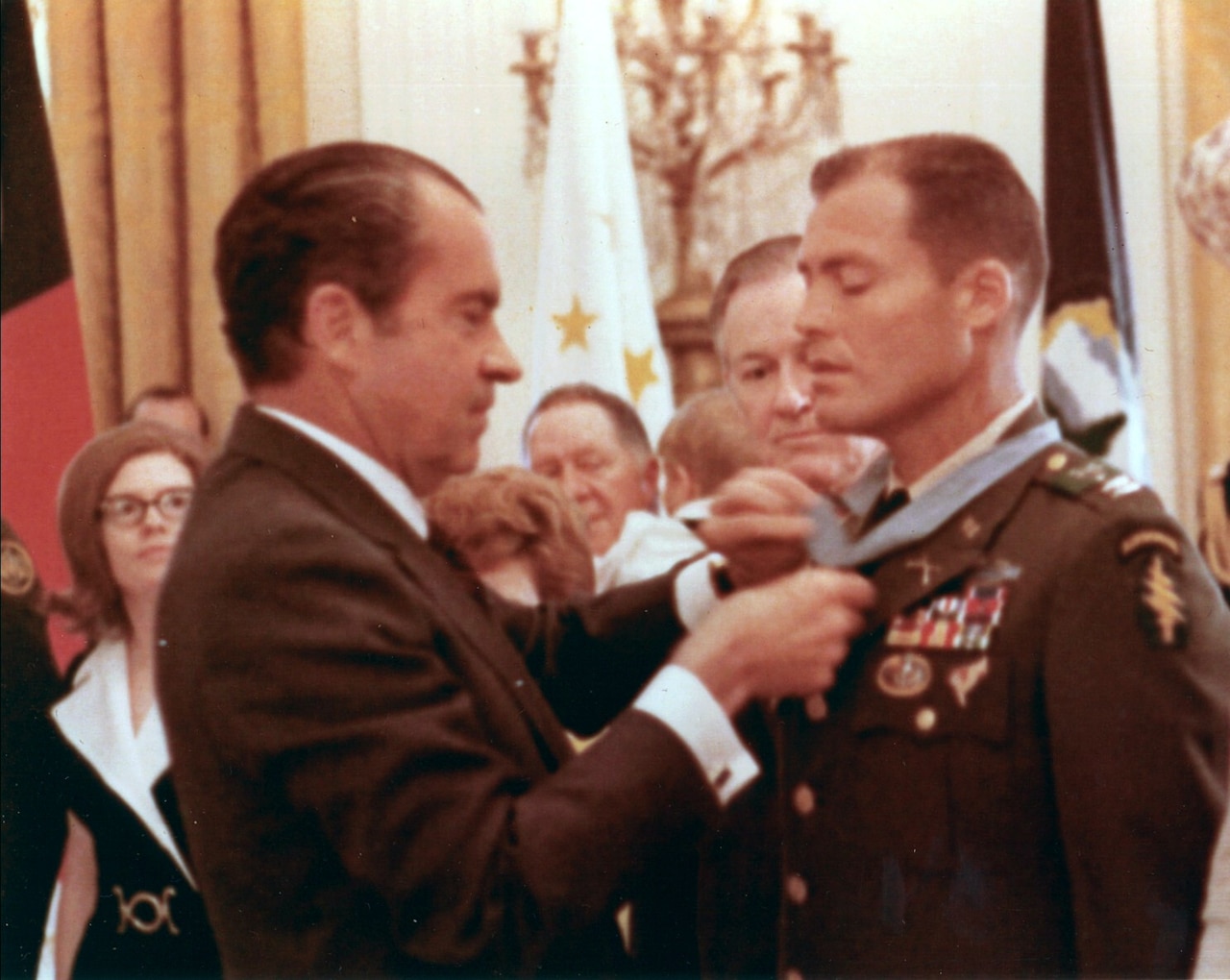 A man puts a ribbon around another man’s neck as others watch.