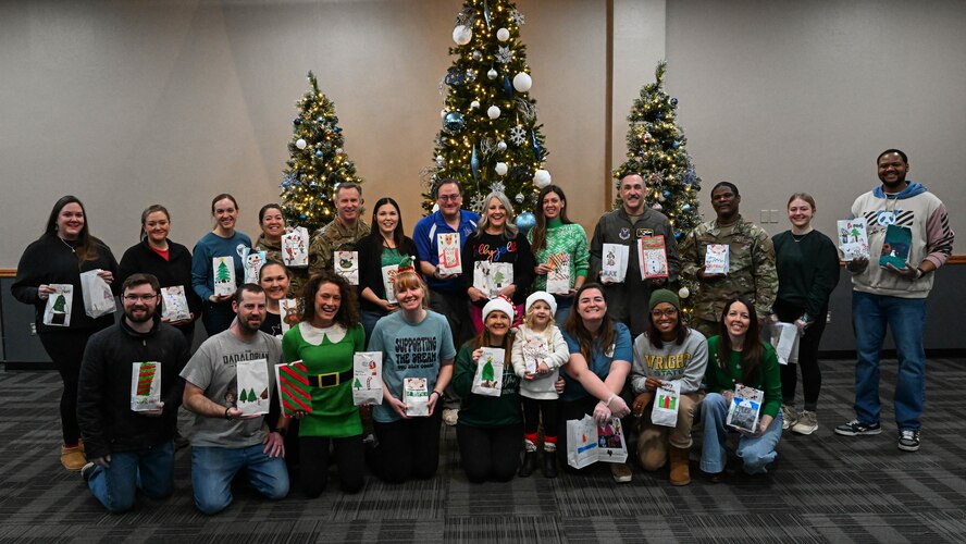 Members of the Minot community, Team Minot leaders, and family members pose for a photo during the Cookie Drive at Minot Air Force Base, North Dakota, Dec. 19, 2024. As part of the Cookie Drive, members of the Minot community, Team Minot leaders, and family members baked and delivered cookies to Airman around Minot AFB. (U.S. Air Force photo by Senior Airman Kyle Wilson)