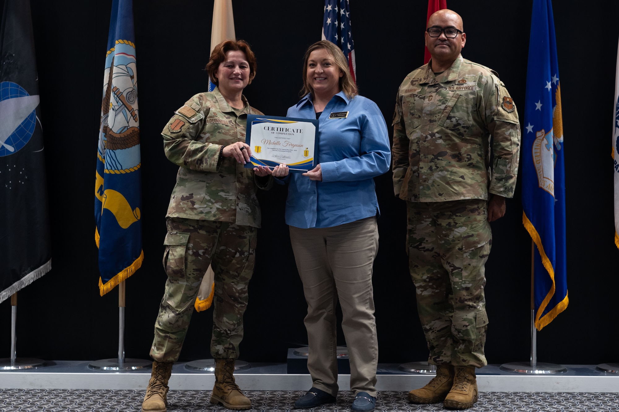 A woman is holding a graduation certificate with two people standing on each side of her.