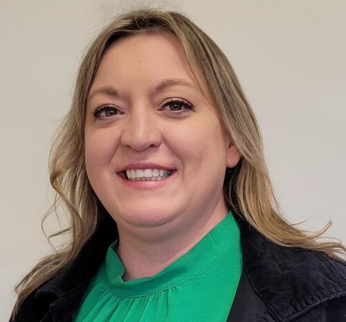 A woman is smiling, looking into the camera.