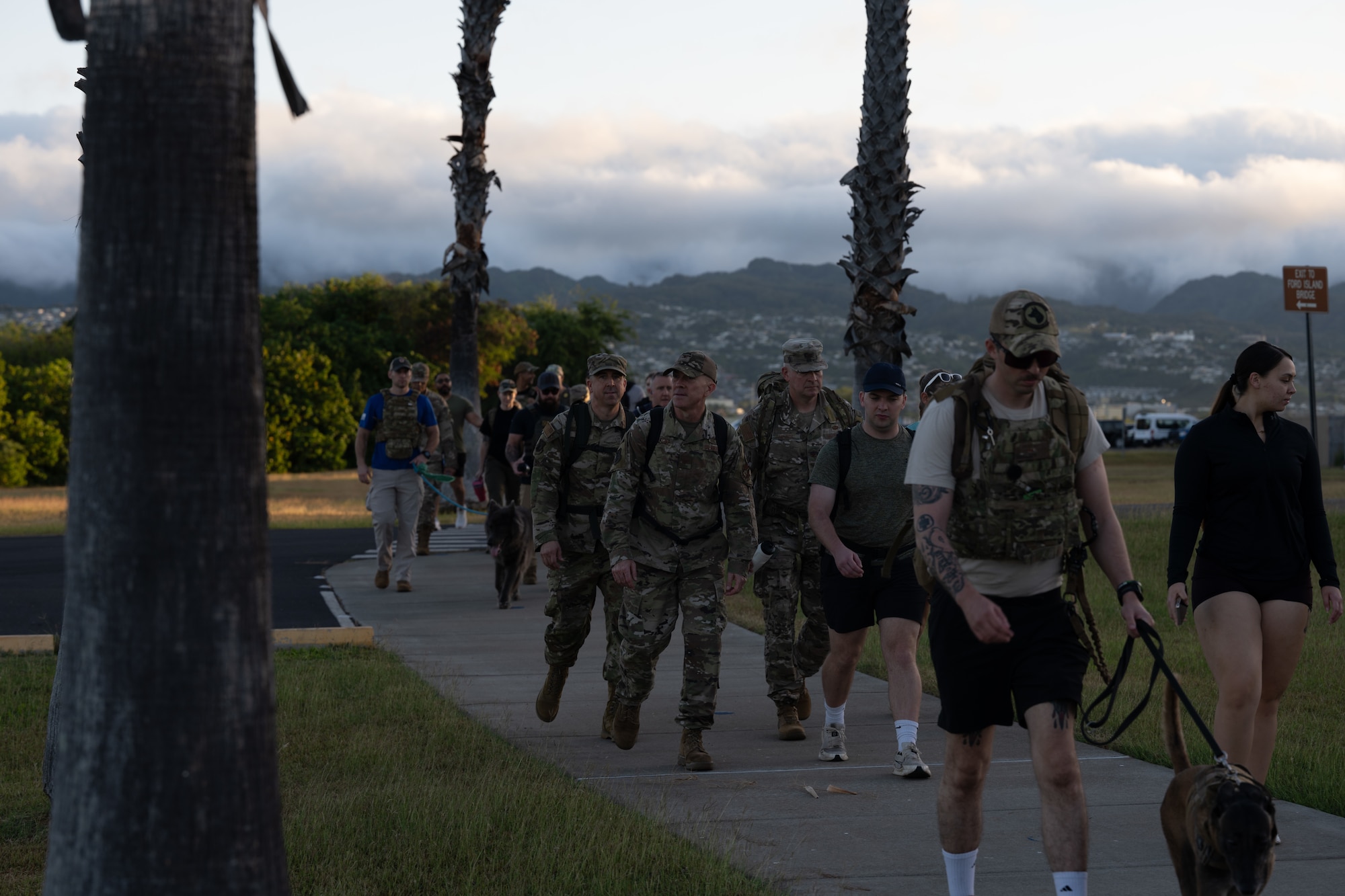 Military personnel walk together in a group with mountains in the background.