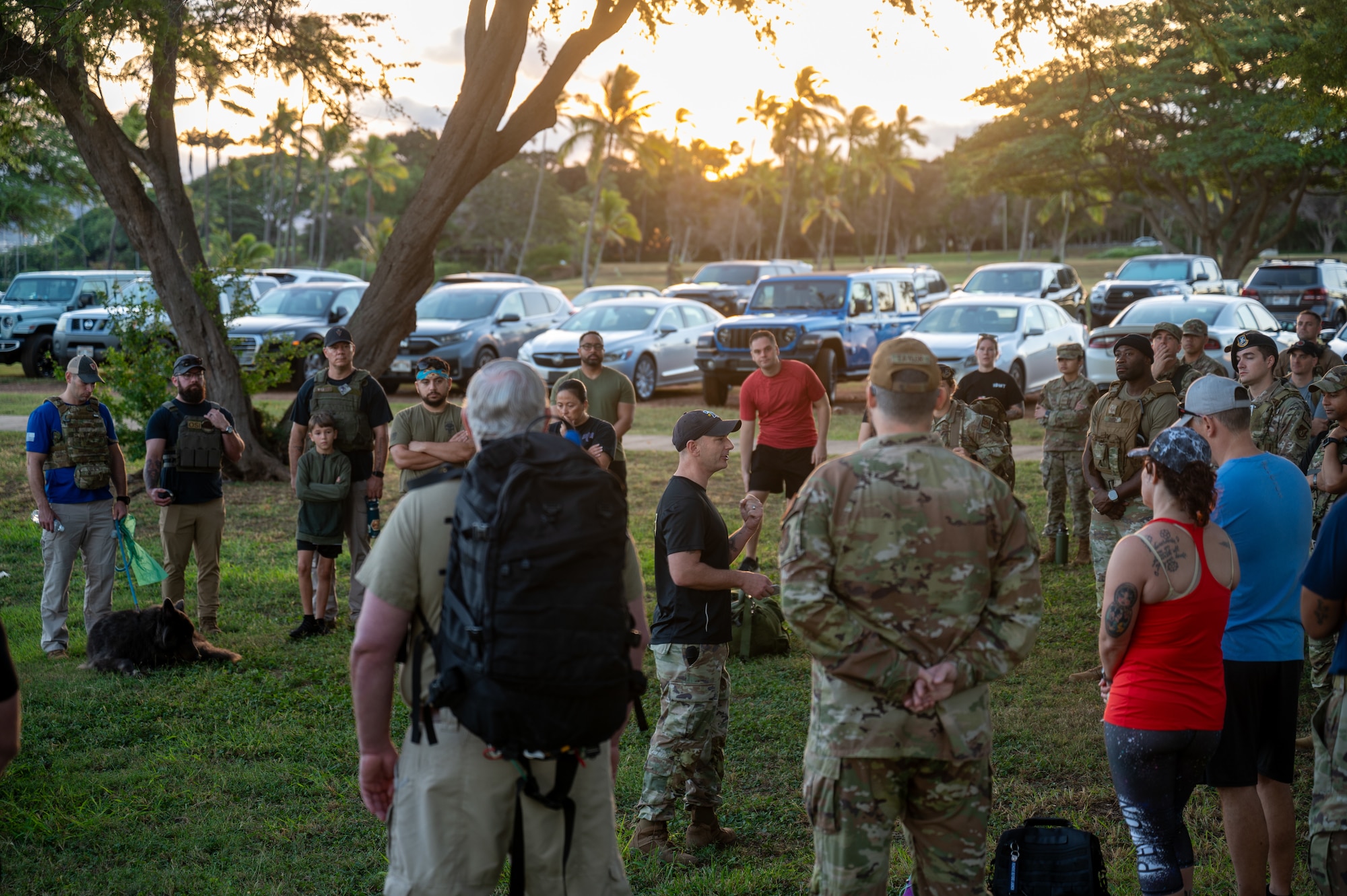 Military personnel walk together in a group during the sunrise on a pave path.