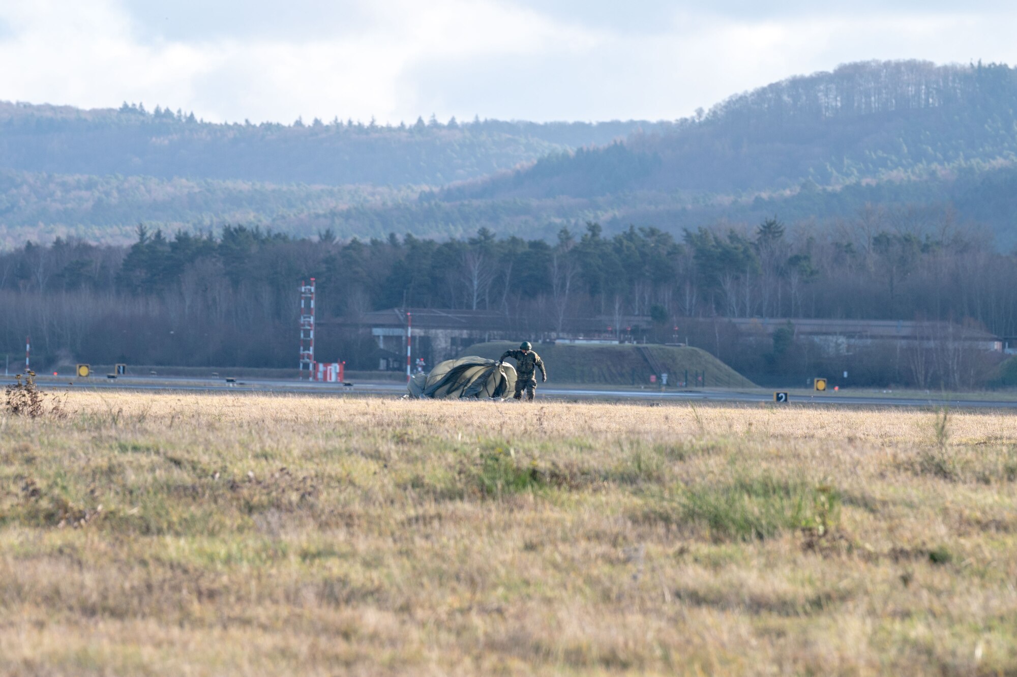 A paratrooper gathers his parachute after a jump.