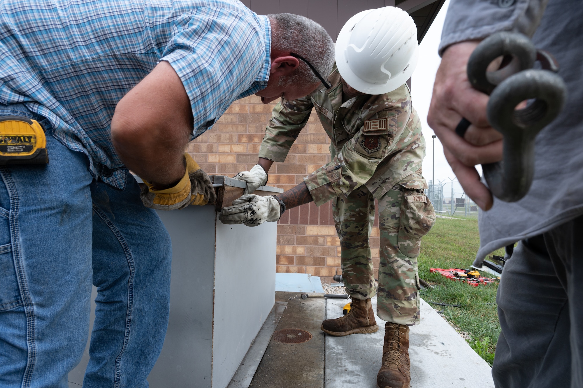 U.S. Air Force Airmen and civilian contractors prepare the base of an air conditioning unit for removal at Whiteman Air Force Base, Mo., Sept. 24, 2024. The replacement of the air conditioning unit allowed for Military Working Dogs to remain in proper conditions within the kennels. (U.S. Air Force photo by Senior Airman Joseph Garcia)