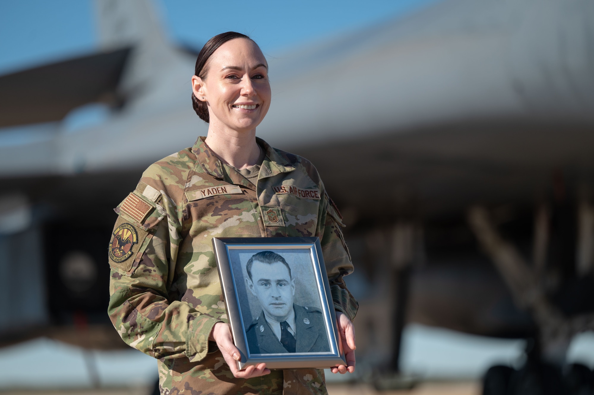 U.S. Air Force Senior Master Sgt Destini Yaden, 9th Bomber Generation Squadron first sergeant, poses with a photo of her grandfather at Dyess Air Force Base, Texas, Dec. 11, 2024. Yaden was selected to be a first sergeant at Nellis AFB, Nevada, the same place her grandfather ended his first sergeant tour. (U.S. Air Force photo by Airman 1st Class Emma Anderson)