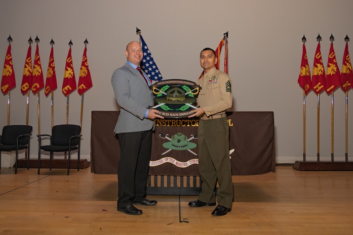 Retired U.S. Marine Corps Maj. Brian A. Kiraly, the guest of honor, left, and the senior enlisted Marine of Marine Corps Recruit Depot San Diego Drill Instructor School, 1st Sgt. Omar Garcia with MCRDSD DI School, pose for a photo during the DI school 1-25 graduation ceremony at MCRD San Diego, California, Dec. 18, 2024. During DI school, Marines developed leadership skills, mastered drill, met physical fitness requirements and learned how to make Marines. Our Marines continue to serve their nation and their Corps through their lived examples of our values and by helping to identify and select potential recruits who may have what it takes to earn the title. (U.S. Marine Corps photo by Lance Cpl. Janell B. Alvarez)