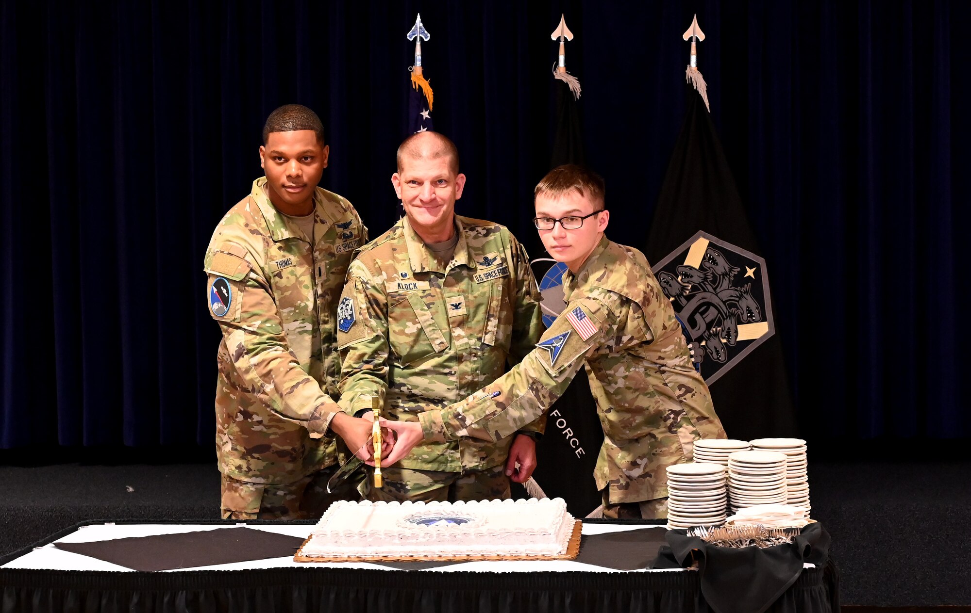 Three Guardians ceremoniously cut a cake during a USSF 5th Anniversary celebration.