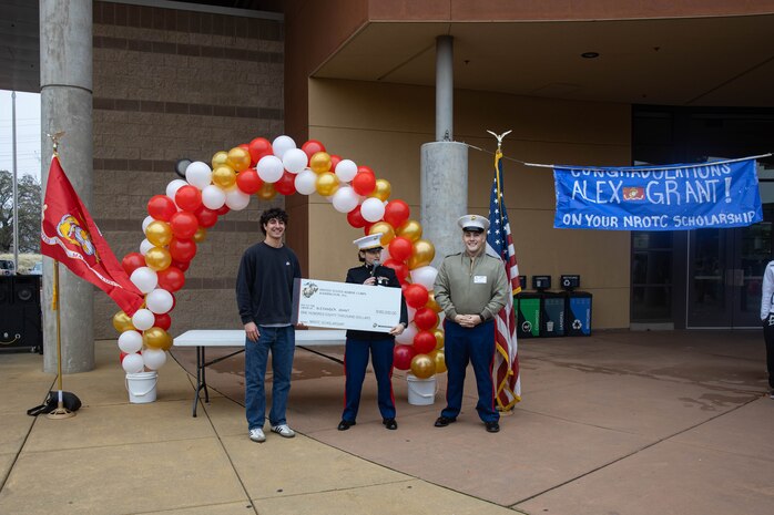 U.S. Marine Corps Capt. Isabel Billinge, center, executive officer of Recruiting Station Sacramento, presents Alexander Grant, recipient of the Naval Reserve Officers Training Corps scholarship, with a ceremonial check during a scholarship presentation in Folsom, California, Dec. 17, 2024. Grant was awarded a $180,000 scholarship into the NROTC program.  The intent of the NROTC Scholarship Program is to educate and train highly qualified young men and women for careers as commissioned officers in the Marine Corps and Naval service. (U.S. Marine Corps photo by Staff Sgt. Ryan Harvey)