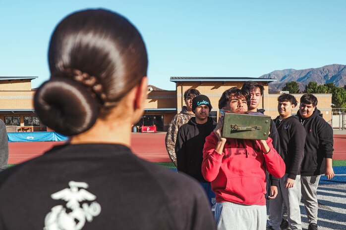 U.S. Marine Corps Pfc. Alexsa RojasRomero, a recruiter assistant with Recruiting Sub-Station Hemet, Recruiting Station San Diego, observes a student performing ammo can lifts during a weight room takeover at Beaumont High School in Beaumont, California, Dec. 16, 2024. A weight room takeover is an event where Marines engage with students in a gym setting, leading workouts and demonstrating fitness techniques as part of a community outreach or recruitment effort. (U.S. Marine Corps photo by Cpl. Alejandro Fernandez)