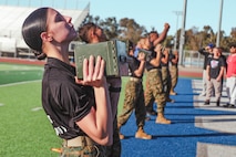 U.S. Marine Corps Lance Cpl. Danielle Truex, a recruiter assistant with Recruiting Sub-Station Hemet, Recruiting Station San Diego, demonstrates how to properly perform ammo can lifts during a weight room takeover at Beaumont High School in Beaumont, California, Dec. 16, 2024. A weight room takeover is an event where Marines engage with students in a gym setting, leading workouts and demonstrating fitness techniques as part of a community outreach or recruitment effort. (U.S. Marine Corps photo by Cpl. Alejandro Fernandez)