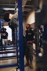 U.S. Marine Corps Pfc. Malachi McLean, a recruiter assistant with Recruiting Sub-Station Hemet, Recruiting Station San Diego, oversees a student performing pull-ups during a weight room takeover at Beaumont High School in Beaumont, California, Dec. 16, 2024. A weight room takeover is an event where Marines engage with students in a gym setting, leading workouts and demonstrating fitness techniques as part of a community outreach or recruitment effort. (U.S. Marine Corps photo by Cpl. Alejandro Fernandez)