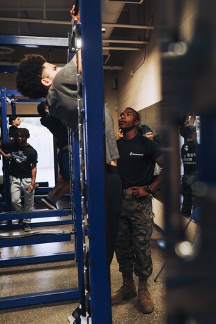 U.S. Marine Corps Pfc. Malachi McLean, a recruiter assistant with Recruiting Sub-Station Hemet, Recruiting Station San Diego, oversees a student performing pull-ups during a weight room takeover at Beaumont High School in Beaumont, California, Dec. 16, 2024. A weight room takeover is an event where Marines engage with students in a gym setting, leading workouts and demonstrating fitness techniques as part of a community outreach or recruitment effort. (U.S. Marine Corps photo by Cpl. Alejandro Fernandez)