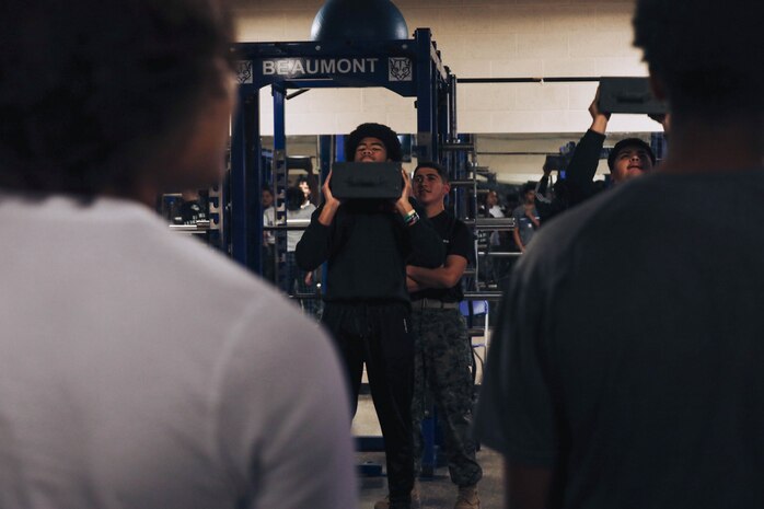 U.S. Marine Corps Pvt. Yair Beatriz, a recruiter assistant with Recruiting Sub-Station Hemet, Recruiting Station San Diego, oversees a student performing ammo can lifts during a weight room takeover at Beaumont High School in Beaumont, California, Dec. 16, 2024. A weight room takeover is an event where Marines engage with students in a gym setting, leading workouts and demonstrating fitness techniques as part of a community outreach or recruitment effort. (U.S. Marine Corps photo by Cpl. Alejandro Fernandez)