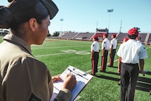 U.S. Marine Corps Sgt. Alanah SunigaJimenez, a canvassing recruiter with Recruiting Sub-Station National City, Recruiting Station San Diego, evaluates cadets during a Junior Reserve Officer Training Corps drill competition at Sweetwater High School in National City, California, Dec. 7, 2024. The Junior Reserve Officer Training Corps drill competition is a formal event where cadets perform synchronized marching routines and precision drill to demonstrate discipline, teamwork and leadership skills. (U.S. Marine Corps photo by Cpl. Alejandro Fernandez)
