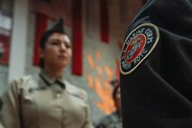 U.S. Marine Corps Sgt. Alanah SunigaJimenez, a canvassing recruiter with Recruiting Sub-Station National City, Recruiting Station San Diego, inspects a cadet's uniform during a Junior Reserve Officer Training Corps drill competition at Sweetwater High School in National City, California, Dec. 7, 2024. The Junior Reserve Officer Training Corps drill competition is a formal event where cadets perform synchronized marching routines and precision drill to demonstrate discipline, teamwork and leadership skills. (U.S. Marine Corps photo by Cpl. Alejandro Fernandez)