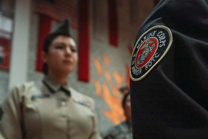 U.S. Marine Corps Sgt. Alanah SunigaJimenez, a canvassing recruiter with Recruiting Sub-Station National City, Recruiting Station San Diego, inspects a cadet's uniform during a Junior Reserve Officer Training Corps drill competition at Sweetwater High School in National City, California, Dec. 7, 2024. The Junior Reserve Officer Training Corps drill competition is a formal event where cadets perform synchronized marching routines and precision drill to demonstrate discipline, teamwork and leadership skills. (U.S. Marine Corps photo by Cpl. Alejandro Fernandez)