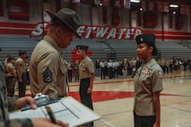 U.S. Marine Corps Staff Sgt. Aaron Placido, a drill instructor with Kilo Company, 3rd Recruit Training Battalion, Marine Corps Recruit Depot San Diego, inspects a cadet's uniform during a Junior Reserve Officer Training Corps drill competition at Sweetwater High School in National City, California, Dec. 7, 2024. The Junior Reserve Officer Training Corps drill competition is a formal event where cadets perform synchronized marching routines and precision drill to demonstrate discipline, teamwork and leadership skills. (U.S. Marine Corps photo by Cpl. Alejandro Fernandez)