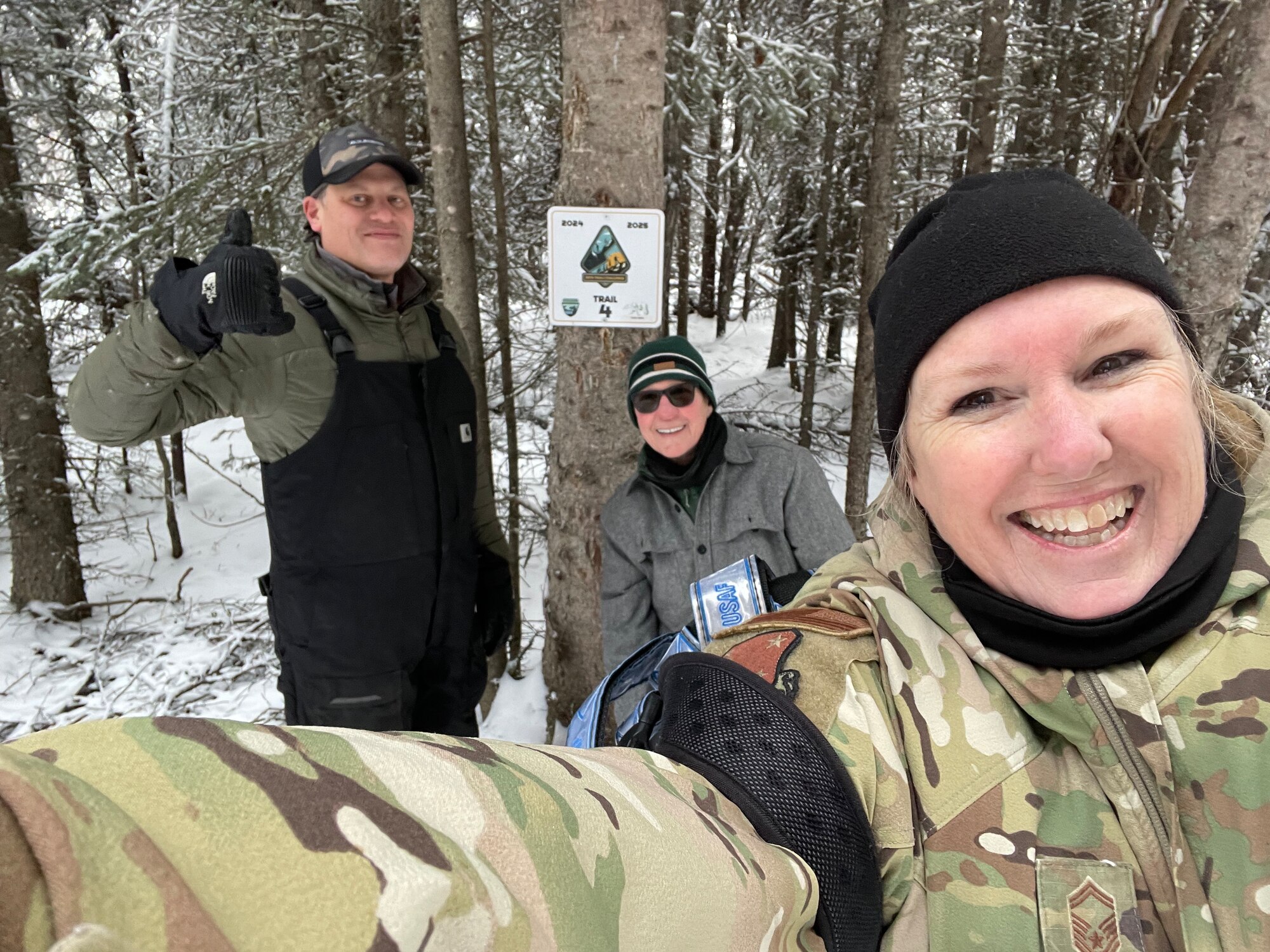 Gene Larocca of the Eielson Air Force Base Natural Resources and Deb Lipyanic of the Alaska Air National Guard, 168th Wing Environmental Office, pose for a selfie with Senior Master Sgt. Julie Avey, 168th public affairs, while showing off the new Winter Trails Challenge sign to kick off the hiking and skiing challenge.