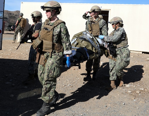 Lt. Cmdr. Mary Ayres and Hospital Corpsman Second Class (HM2) Caleb Coker carries a high-fidelity simulated manikin into an ambulance after receiving Role 2 care while Cmdr. Sasha Smith gives ventilation to the simulated patient during a training evolution on Bravo 1 Range conducted by Naval Expeditionary Medicine Warfighter Development Center (NEMWDC) on Dec. 16. The Expeditionary Resuscitative Surgical System (ERSS) team comprised of a seven-man team from Camp Lejeune is preparing for an upcoming deployment in Spring 2025. Ayres is a general surgeon serving at Navy Medicine Readiness and Training Command (NMRTC) Camp Lejeune, N.C. Coker works as a respiratory technician also with NMRTC Camp Lejeune. Working at the same facility, Smith is a certified registered nurse anesthetist.