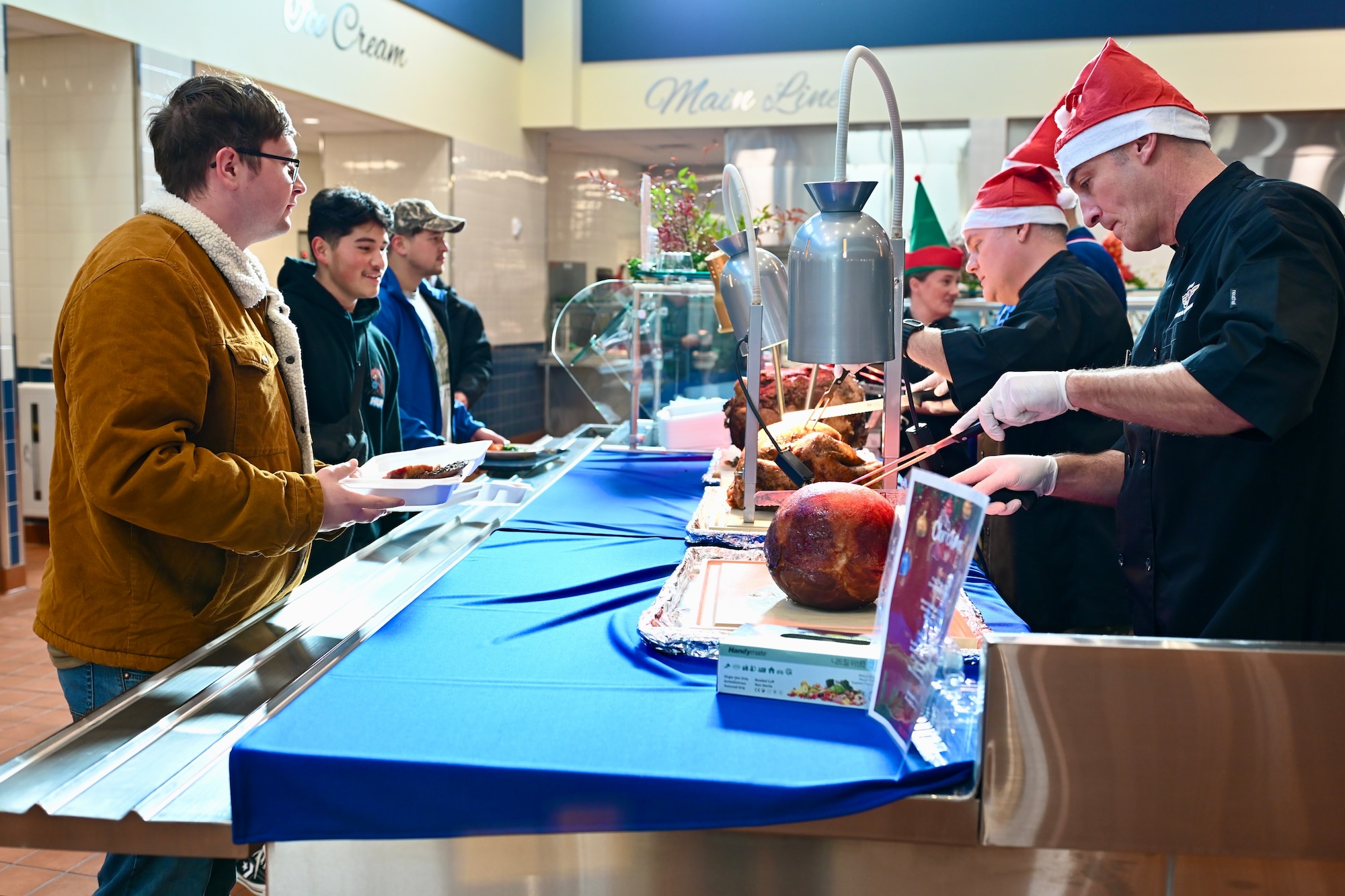 U.S. Air Force Chief Master Sgt. Nathan Chrestensen, 8th Fighter Wing command chief, and Col. Jason Monaco, 8th FW deputy commander, serve meat at the carving station during Kunsan’s holiday meal, at the O’Malley Dining Facility.