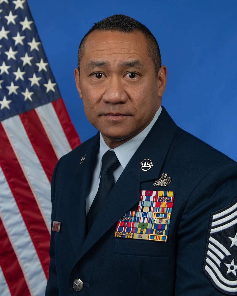 Chief Master Sergeant Jeffrey Lee stands in front of a blue background, looking into the camera.