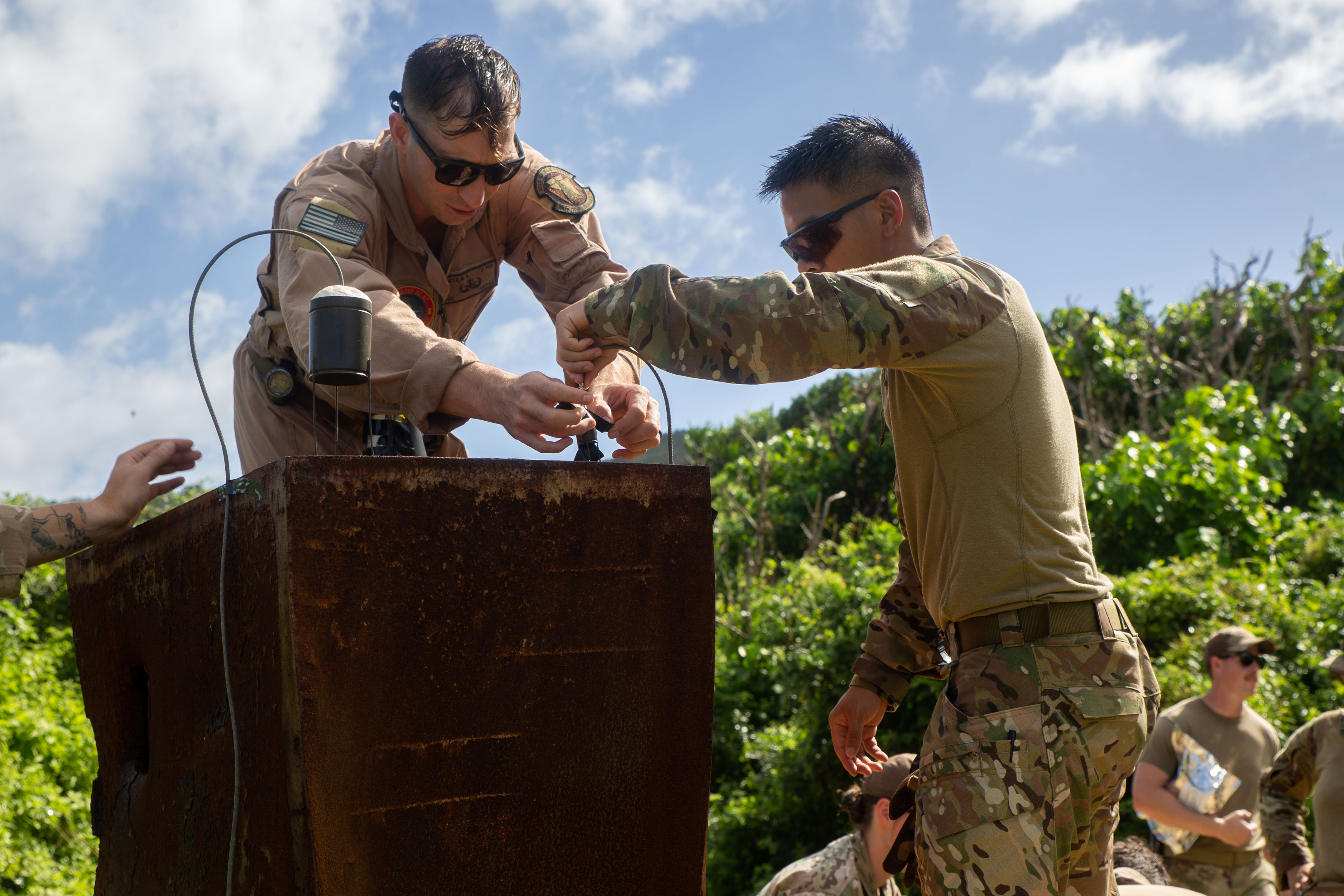 U.S. Marines with Marine Corps Base Camp Blaz and U.S. Airmen with the 36th Civil Engineer Squadron, all explosive ordnance disposal technicians, carefully place C4 charges on a safe used for training on Andersen Air Force Base, Guam, Dec. 13, 2024. Marines and Airmen participated in a joint service EOD range to maintain tactical proficiency and build interoperability between the EOD teams. (U.S. Marine Corps photo by Lance Cpl. Afton Smiley)