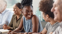 A diverse group of men and women at a desk smiling and talking with each other