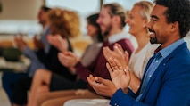 A group of business men and women sitting at a conference clapping