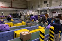 U.S. Marines and master labor contractors with Marine Corps Installations Pacific Marine Corps Base Camp Butler Postal, sort mail bags and parcels at the MCIPAC Postal Operations Center on Camp Foster, Okinawa, Japan, Dec. 9, 2024.