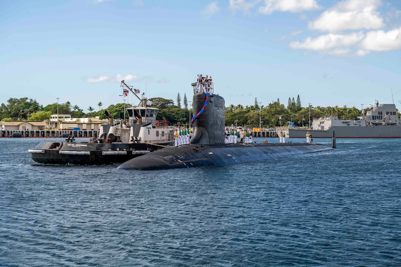 A submarine is partly submerged next to a tugboat near a shoreline.