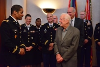 President Jimmy Carter stands on the right smiling while facing a Georgia National Guardsman