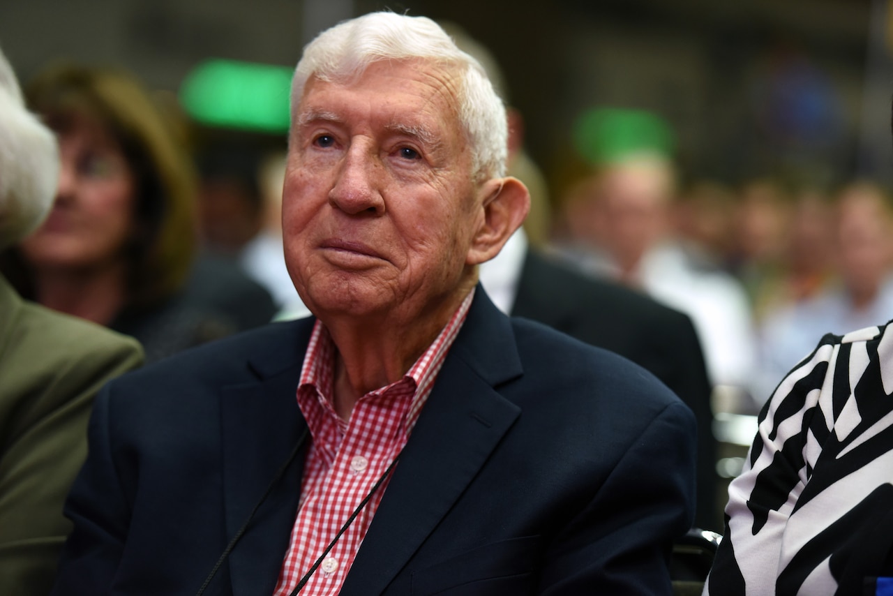 A man smiles as he sits in a crowd.