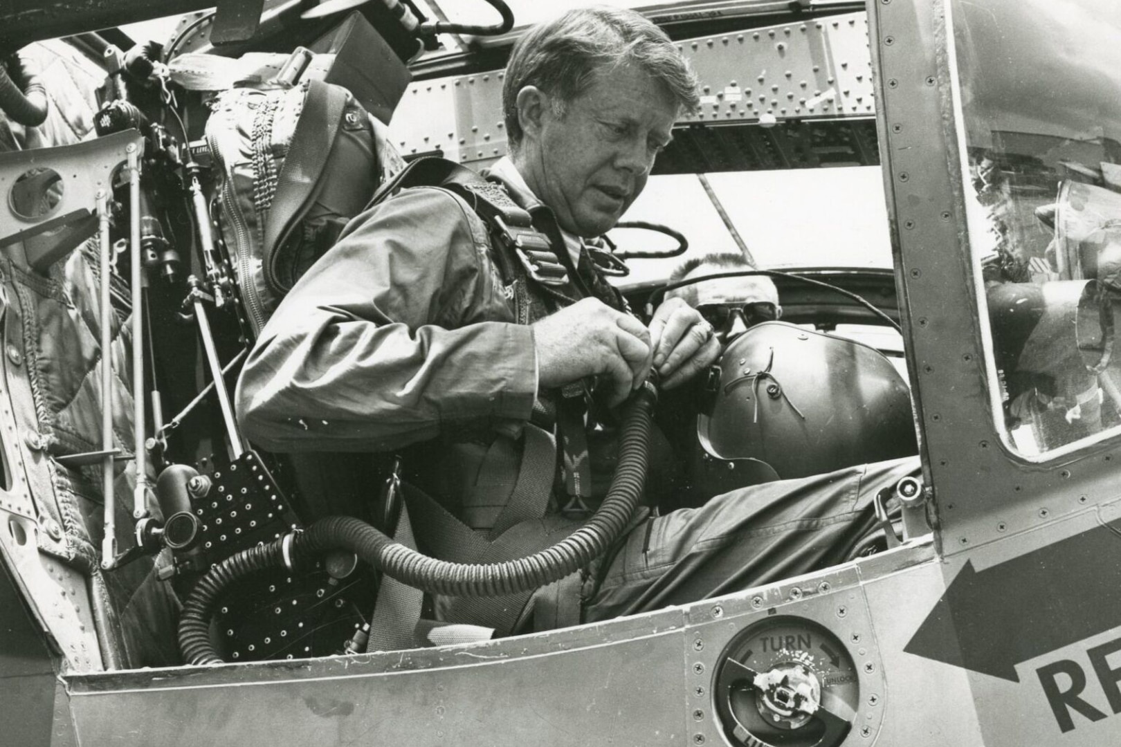 A man suits up in an aircraft.