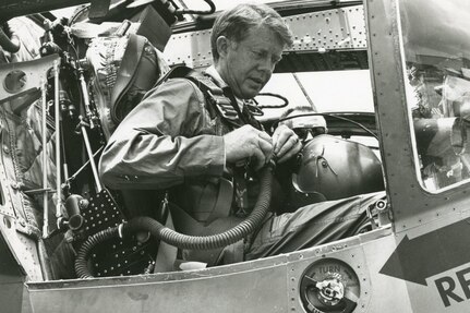 A man suits up in an aircraft.