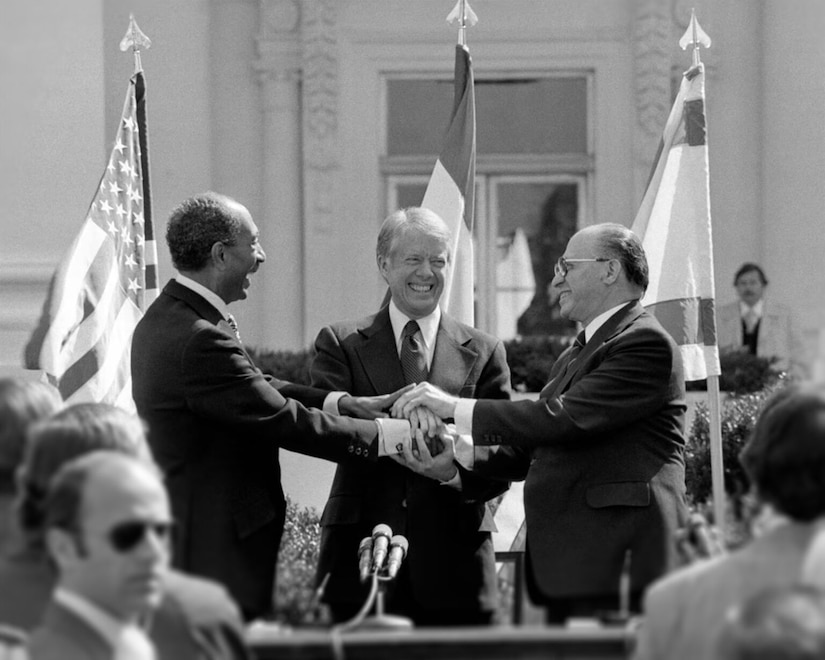 Three men clasp hands.