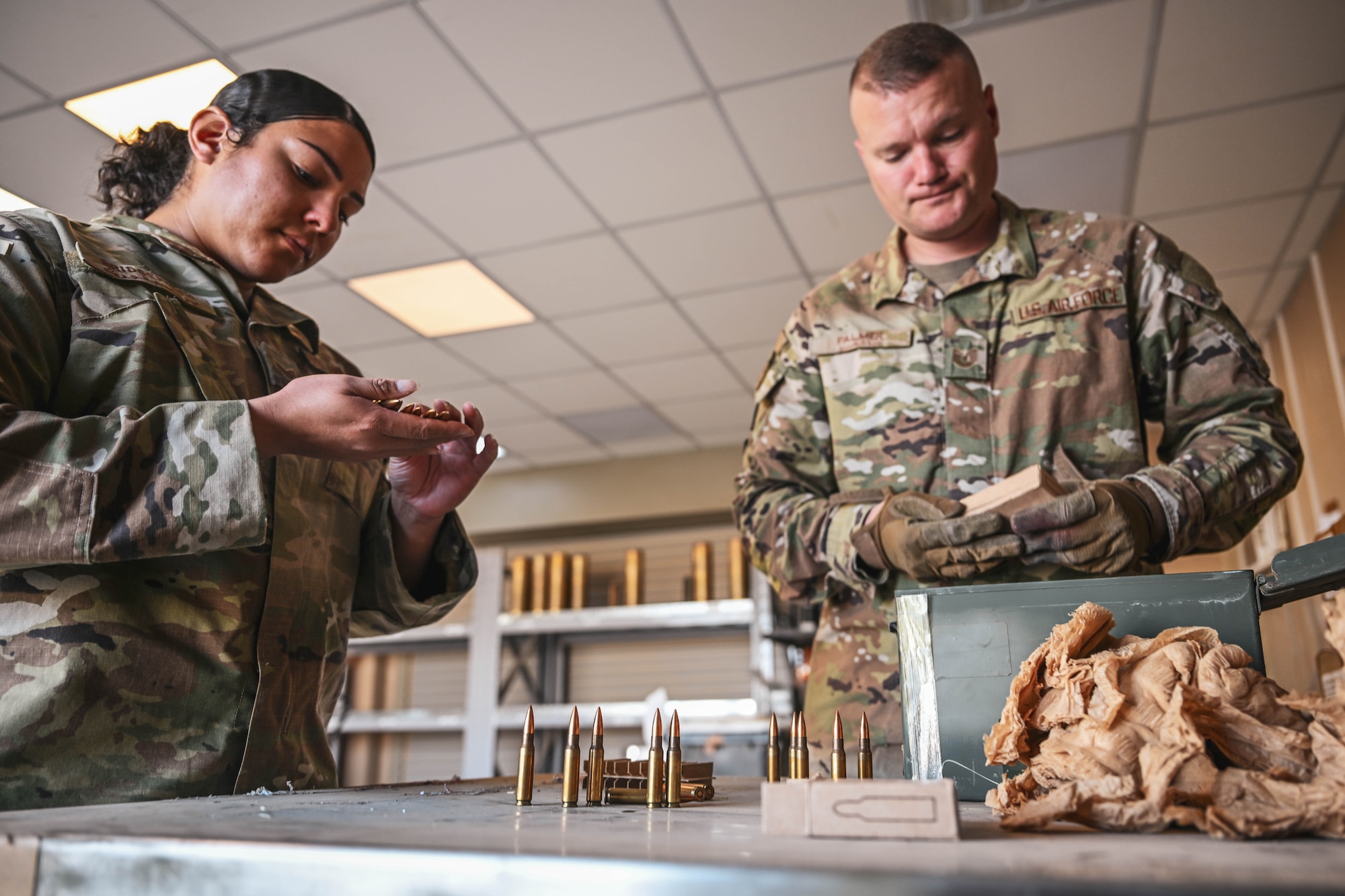 Two people in uniform look at bullets.