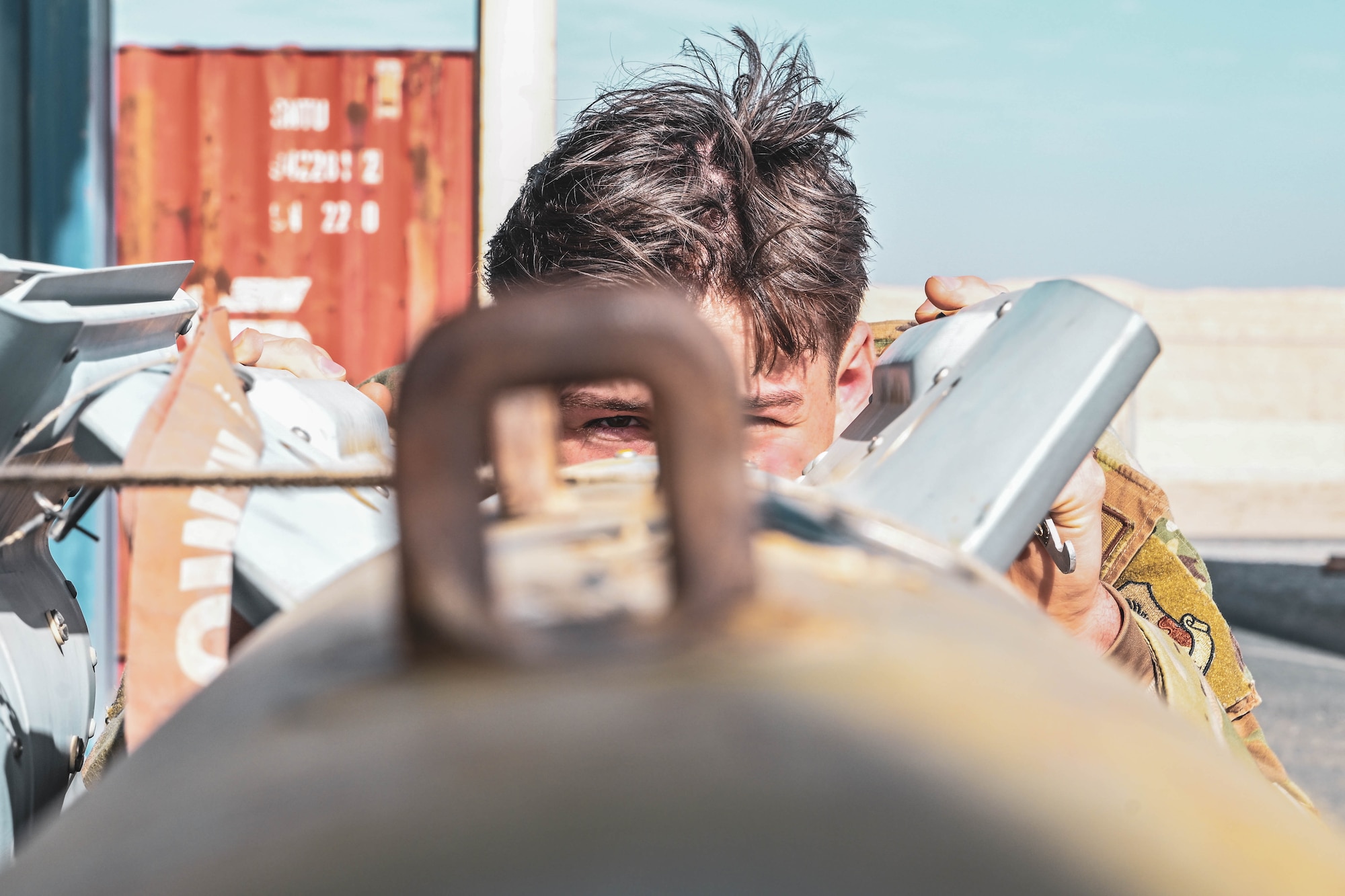 A man in uniform looks through a lug on an ordnance.