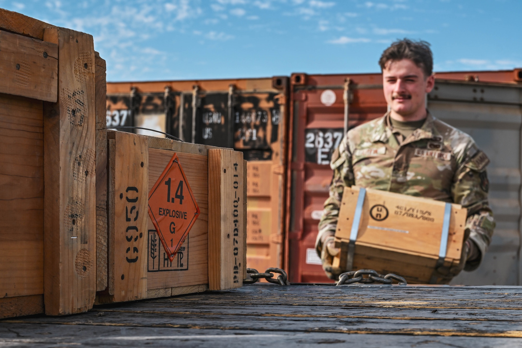 A man in uniform carries a box toward another group of boxes.