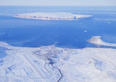 A snow covered landscape with open water in the background. The snow hides the buildings and runway of the military base.