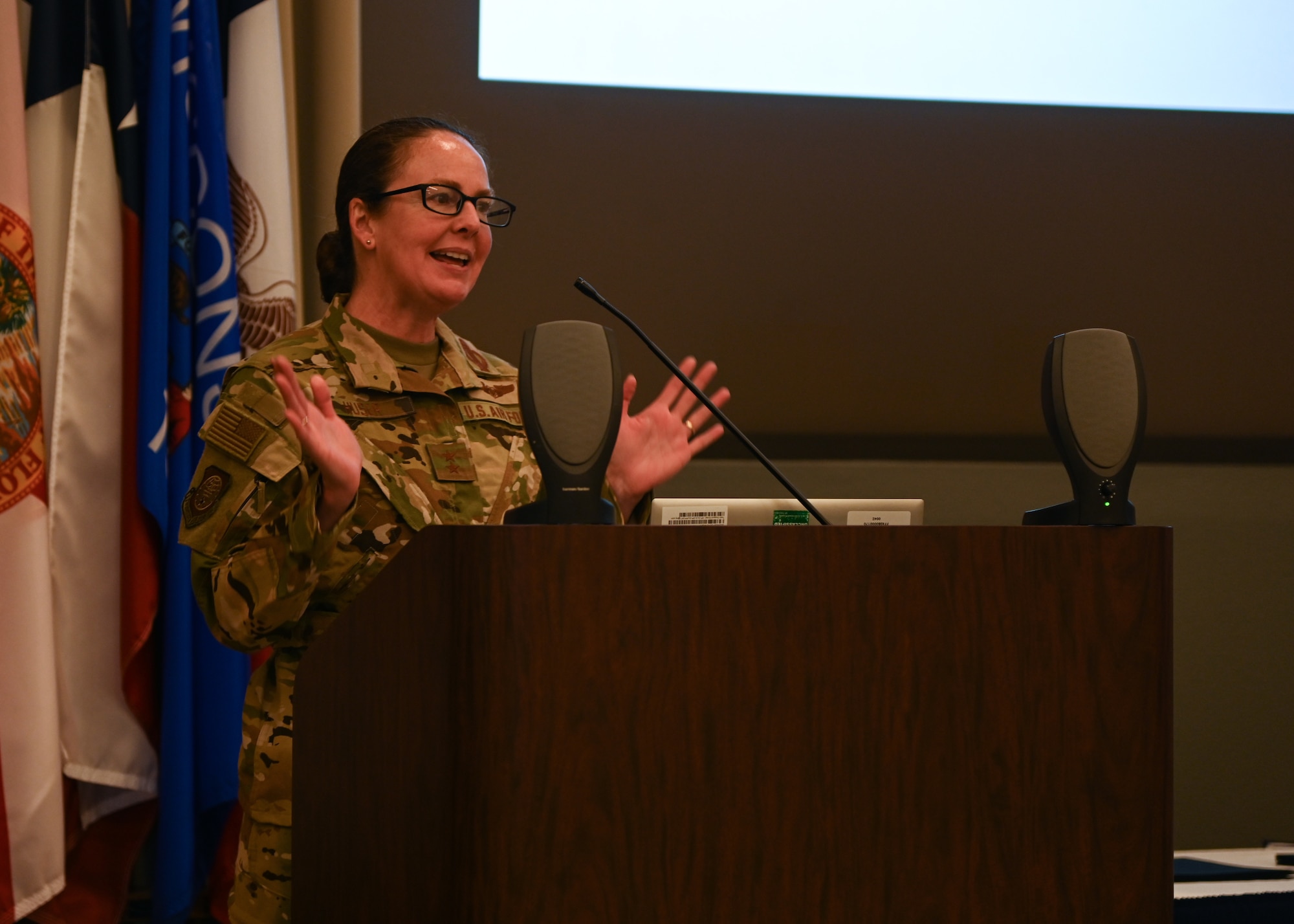 a female major general speaks to military members in a large auditorium during a missile training graduation