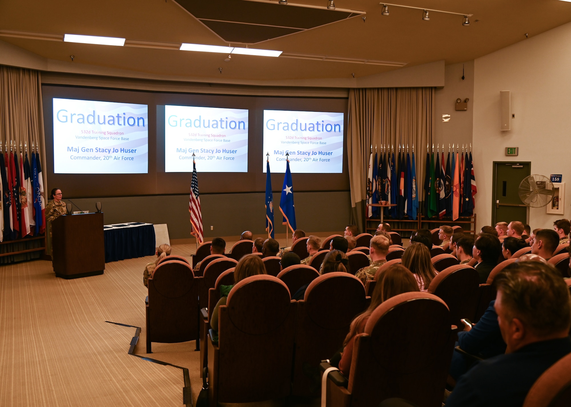 a female major general speaks to military members in a large auditorium during a missile training graduation