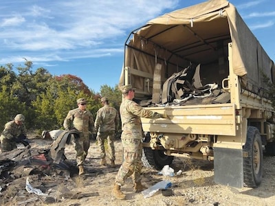 Soldiers load an Army truck with what looks like trash