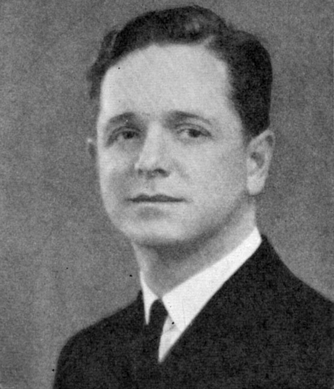 A man in a suit poses for a photo.