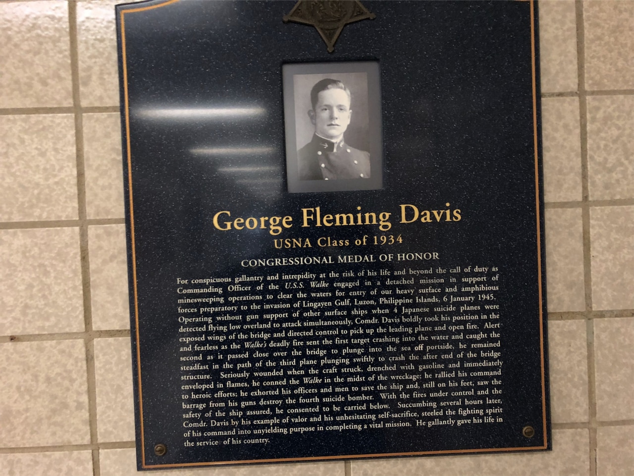 A plaque with a photo and lots of writing hangs on a wall.