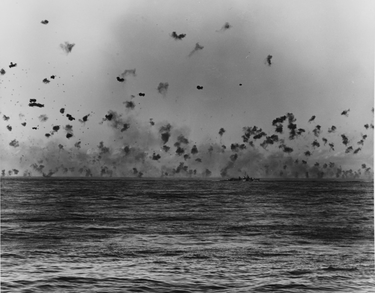 Little puffs of smoke are littered across the sky from ship gunshot.