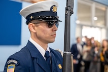 A photo of a member of the U.S. Coast Guard standing still with a ceremonial rifle.